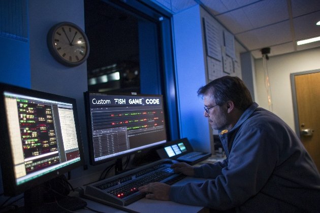 Developer coding custom fish game on dual monitors at night