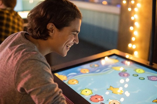 Young man smiling while playing interactive fish touchscreen game