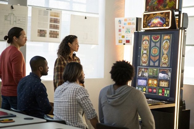 Diverse team reviewing ornate slot machine prototype display