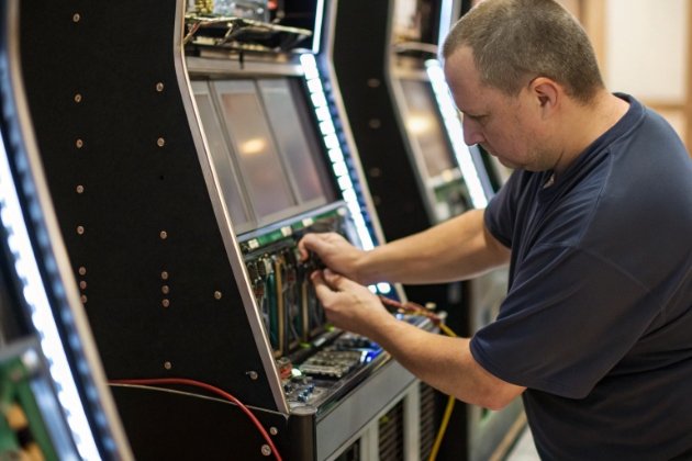 Engineer installing circuit boards inside gaming cabinet